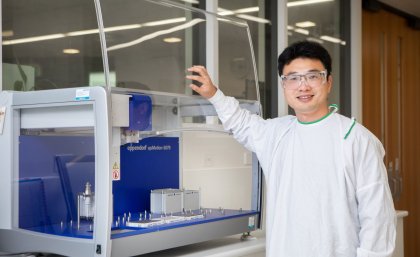 Dr Chun Xu in the laboratory with his hands on a piece of equipment